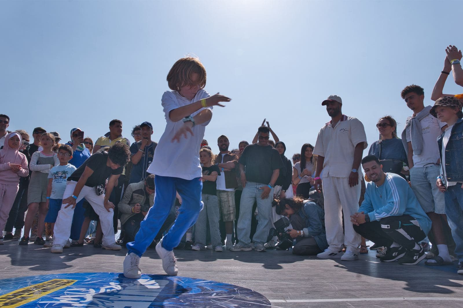 Un jeune danseur au centre du cercle, devant une foule d'enfants.
