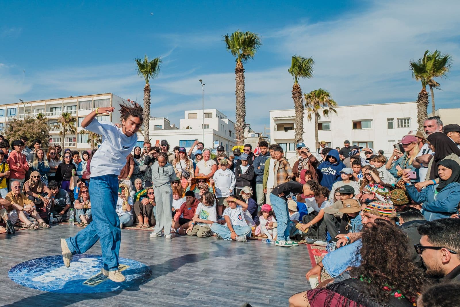 Le cercle de la Swira Breaking Jam sur la corniche d'Essaouira, le public assis autour d'un danseur.